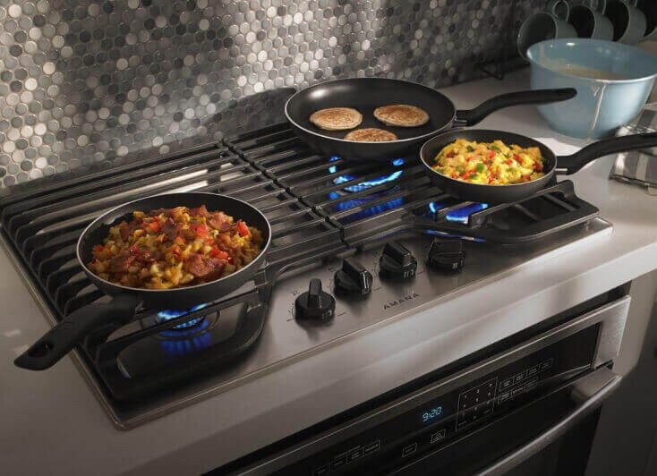 An Amana® cooktop with three burners cooking. An Amana® cooktop with three burners cooking.