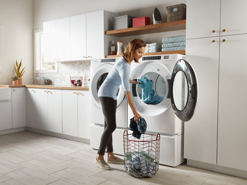 Woman loading laundry into a white washer and dryer Woman loading laundry into a white washer and dryer