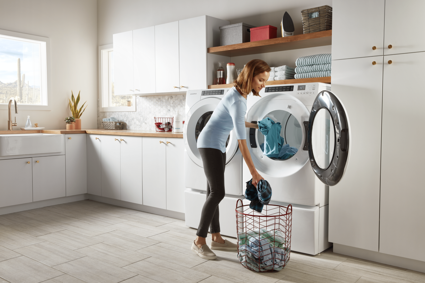 Woman loading laundry into a white washer and dryer Woman loading laundry into a white washer and dryer