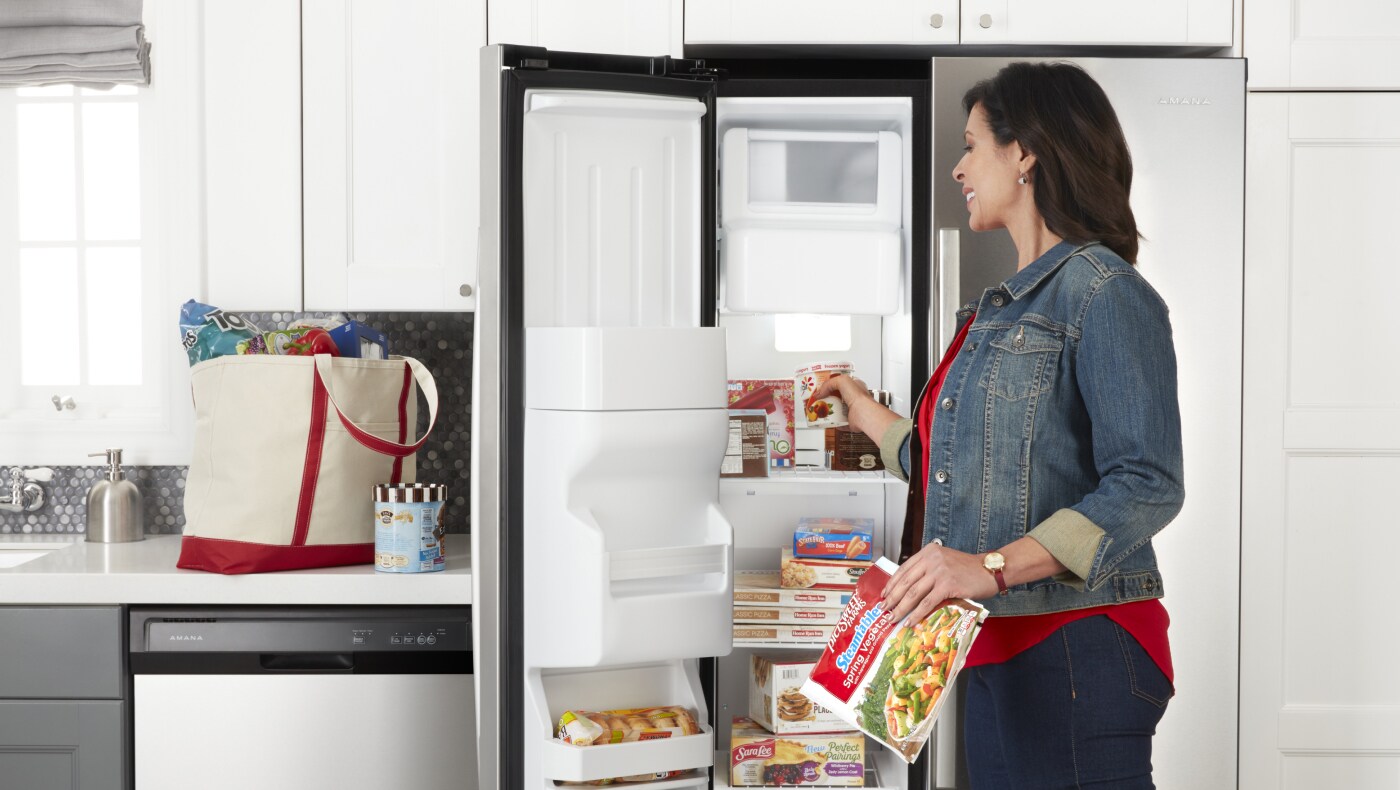Person putting food in Amana® side-by-side refrigerator  Person putting food in Amana® side-by-side refrigerator
