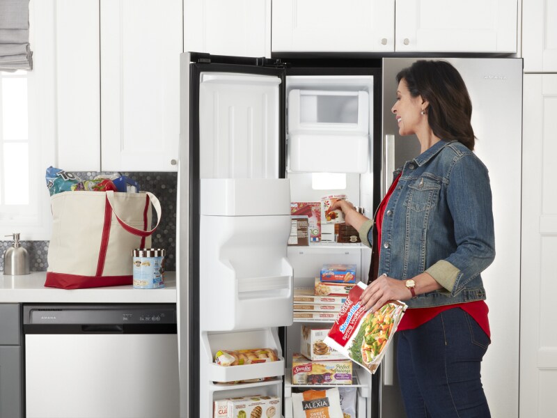 Person putting food in Amana® side-by-side refrigerator Person putting food in Amana® side-by-side refrigerator