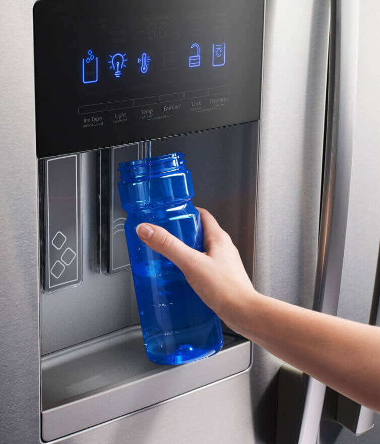 Person filling a water bottle from a refrigerator water dispenser