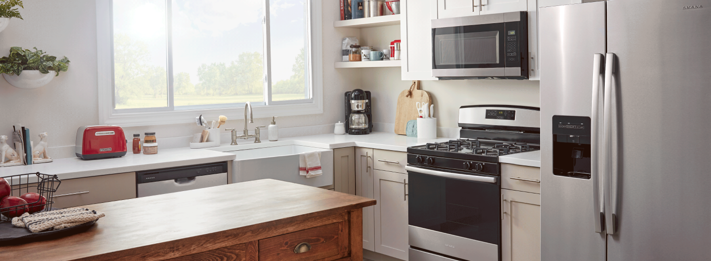 An Amana® dishwasher, range and refrigerator in a kitchen.