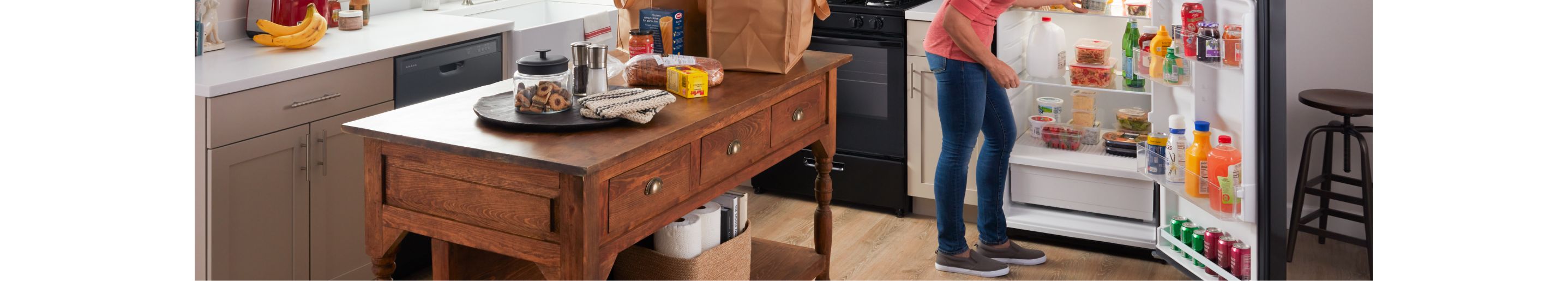 A person putting groceries into an Amana® refrigerator.