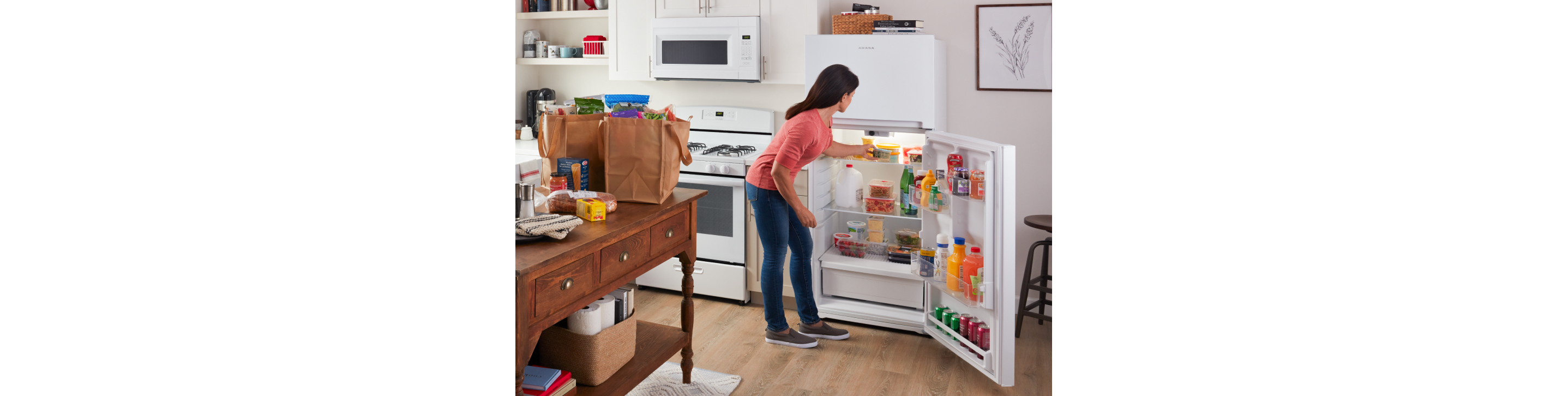 A person putting groceries into an Amana® refrigerator.